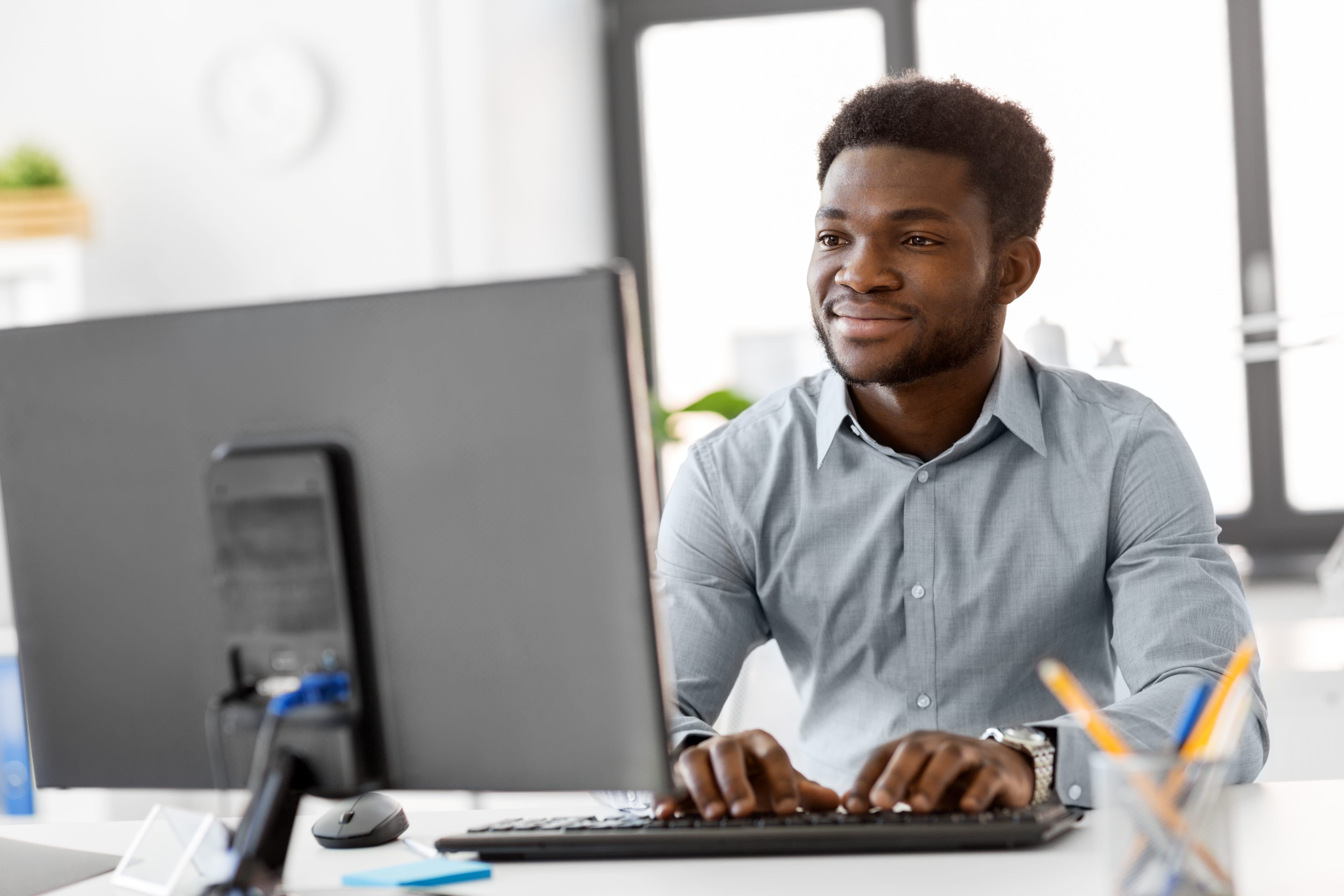 A young professional sitting at a computer and typing on a keyboard.